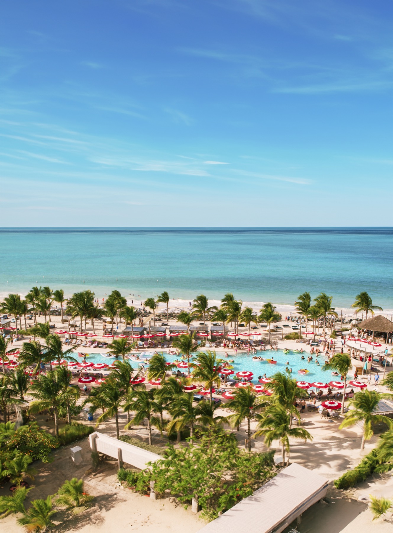 Turquoise water, palms and beach umbrellas at the Virgin Voyages Beach Club in Bimini